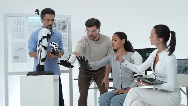 Team tests gloved robotic hands together, an engineer in goggles and a scientist in glasses guide a volunteer's bionic hand gestures in the lab
