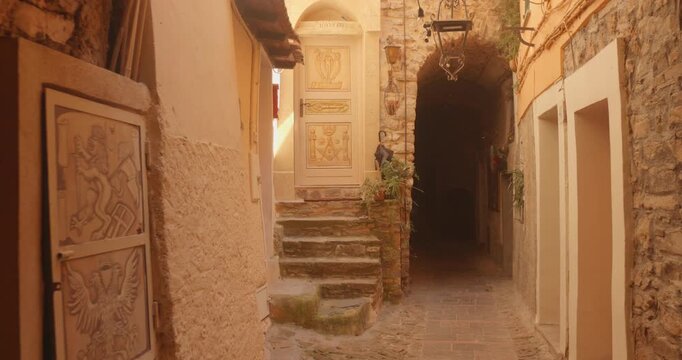 Stone steps, decorated doors with eagle lion emblems and an arched passage in the medieval village of Perinaldo, Italy