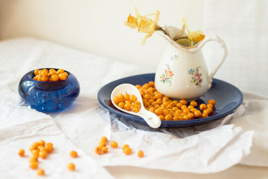 Sea buckthorn harvest on a blue plate against a light background