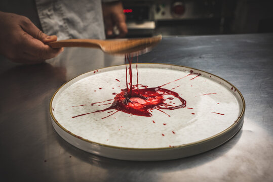 White dessert with berry sauce and chocolate garnish