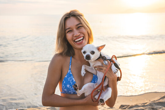 Young Vietnamese woman holding a small dog at the beach
