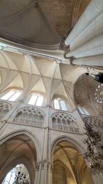 Dynamic upward view across the pale ribbed vaults, clerestory windows and chandeliers of Burgos Cathedral in Spain.