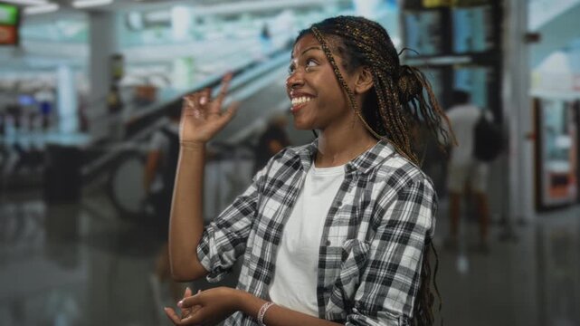 African american woman smiling with palms up presenting at airport terminal; travel welcome arrival joy.