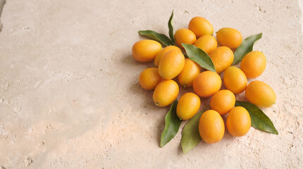 Obraz premium Kumquats with green leaves arranged on limestone surface