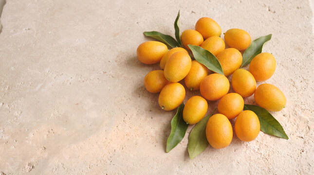 Kumquats with green leaves arranged on limestone surface