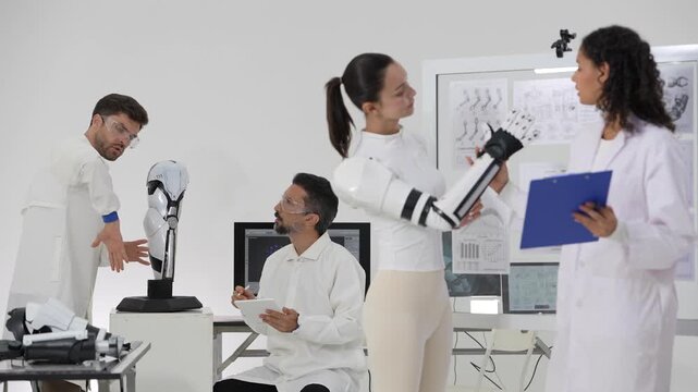 Wide view of a busy robotics lab: a woman wearing a bionic arm demonstrates hand movement to a scientist while engineers work around her