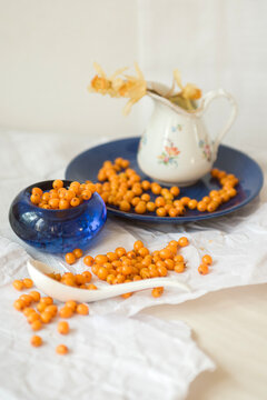 Sea buckthorn harvest on a blue plate against a light background
