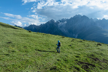 Fototapeta premium Backpacking woman hiking on flowering grassland mountain top
