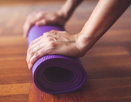 Hands rolling up yoga mat after workout