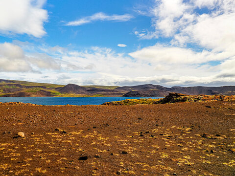 Wild Icelandic landscape against blue, cloudy sky. Kleifarvatn is the largest lake on the Reykjanes Peninsula, southwest of Iceland. Surrounded by lava fields, active volcanoes run along its length.