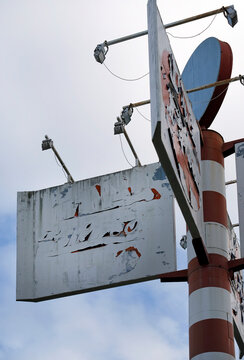Faded and weathered billboard on a large metal pole
