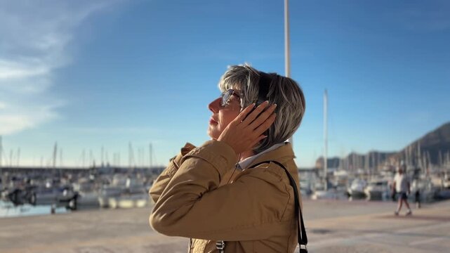 Mujer +50 con auriculares en el paseo mar&iacute;timo junto al mar