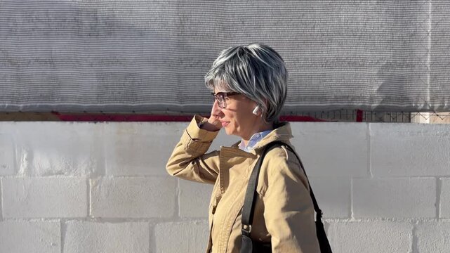 Mujer +50 caminando por zona urbana de derecha a izquierda