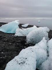 Black-sand beach in Iceland, known as "Diamond Beach", famed for the glistening fragments of broken icebergs drifted ashore from Jökulsárlón - "Glacial River Lagoon". Crystals of melting ice, close-up © LifeCollectionPhoto