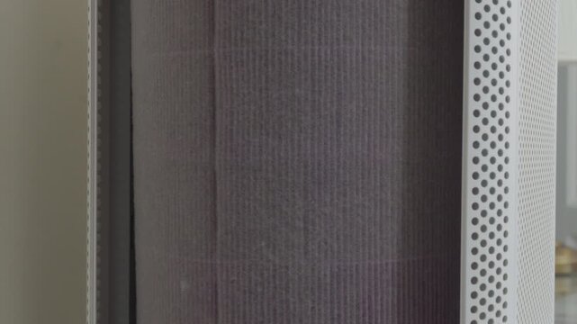 A dusty air filter sits inside a white air purifier in a quiet room. It traps pollution to keep the indoor air clean and healthy. Seeing it work gives a feeling of relief and comfort.