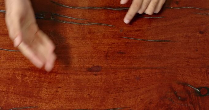 Close up of people talking to the camera, pointing at wooden table, hands indicating specific spots,