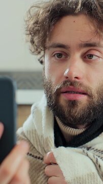 Vertical video. Man with running nose, caughing having video call with doctor while staying at home. Patient video conferencing with general practitioner on smartphone.
