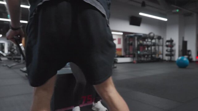 Male personal trainer coaches a pregnant client through a controlled kettlebell goblet squat to a box in slow motion.