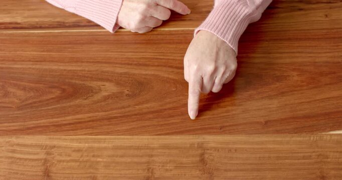 Close up of people talking to the camera, hands of elderly person resting on wooden table, wearing s