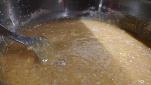 Close up of dough ingredients being mixed and stirred in stainless steel bowl, changing from flour and liquid into a thick pale batter during food preparation
