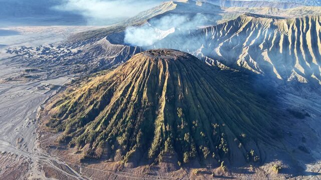 Aerial view of Gunung Batok deeply eroded volcanic slopes, ash plain, crater, and steaming mountain landscape in Indonesia.