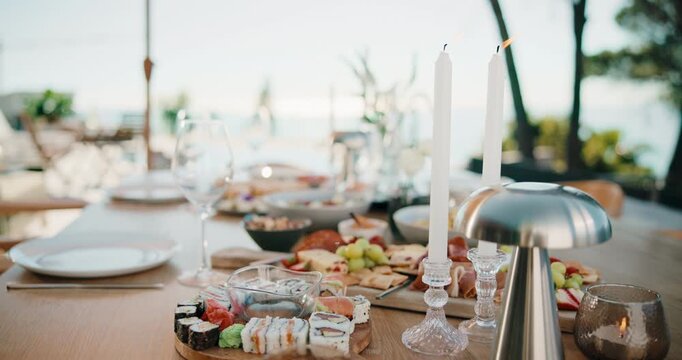 Party, meal or charcuterie board outdoor with candles, sushi arrangement or table setup at gathering. Celebration, nutrition or catering with platter, appetizer or assorted food in backyard event.