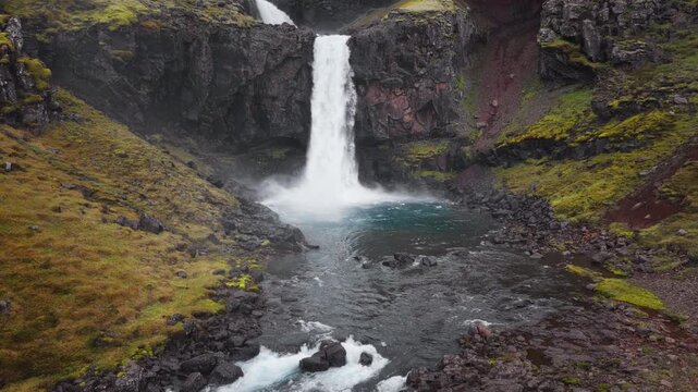 Aerial drone footage of H&aelig;nubrekkufoss Waterfall on the Berufjar&eth;ar&aacute; River, East Iceland, approaching the falls, flying overhead and following the dramatic cascades.