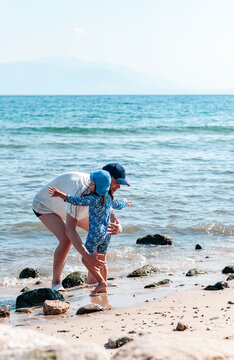 Father Carrying His Little Daughter in His Arms on a Sunny Beach