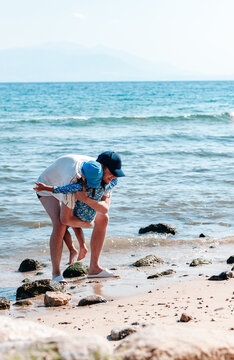 Father Carrying His Little Daughter in His Arms on a Sunny Beach
