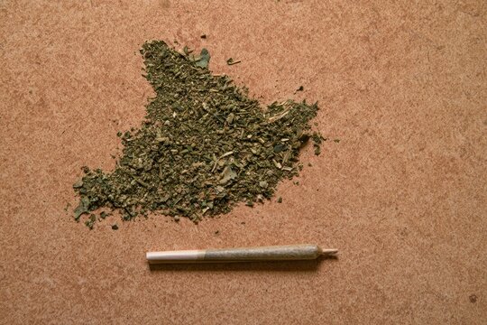 Ground Cannabis and Pre-rolled Marijuana Joint on a Textured Surface