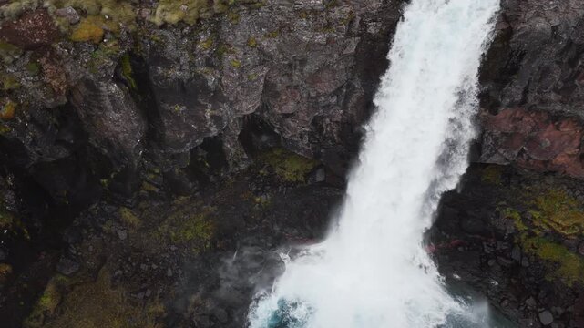 Aerial drone footage of H&aelig;nubrekkufoss Waterfall on the Berufjar&eth;ar&aacute; River, East Iceland, approaching the falls, flying overhead and following the dramatic cascades.