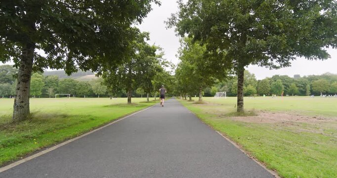 Pathway in park surrounded by lush green trees, perfect for jogging