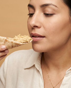 Sensory woman eats a flatbread wrap, with closed eyes in soft beauty lighting