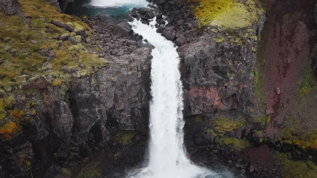 Aerial drone footage of H&aelig;nubrekkufoss Waterfall on the Berufjar&eth;ar&aacute; River, East Iceland, approaching the falls, flying overhead and following the dramatic cascades.