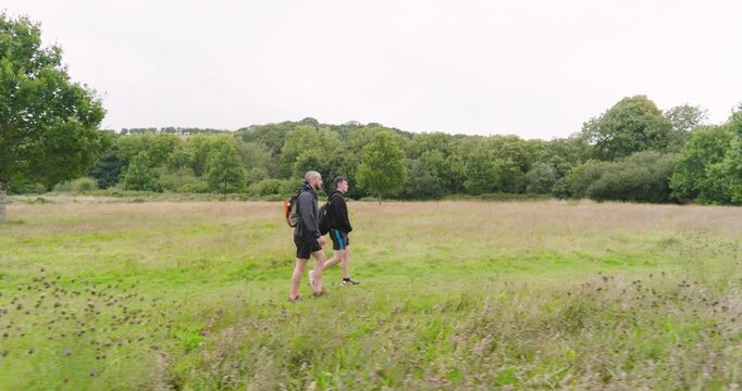 Two people walking through lush green field, enjoying nature and fresh air on cloudy day