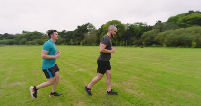 Two men jogging together on grassy field, enjoying outdoor exercise