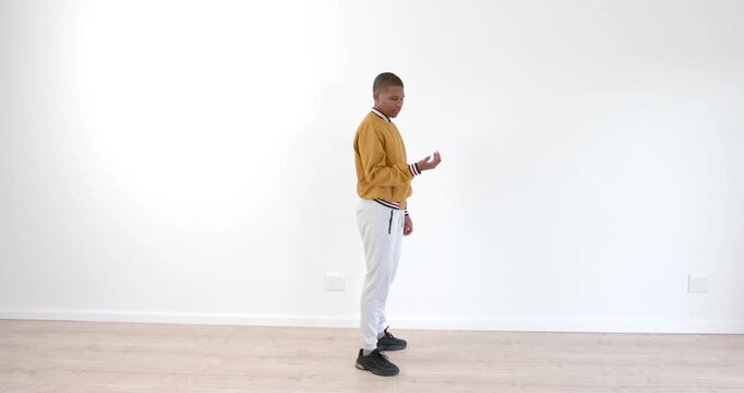 Young boy in casual clothes practicing dance moves in empty room