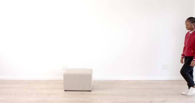 African American woman walking confidently towards ottoman in minimalist room