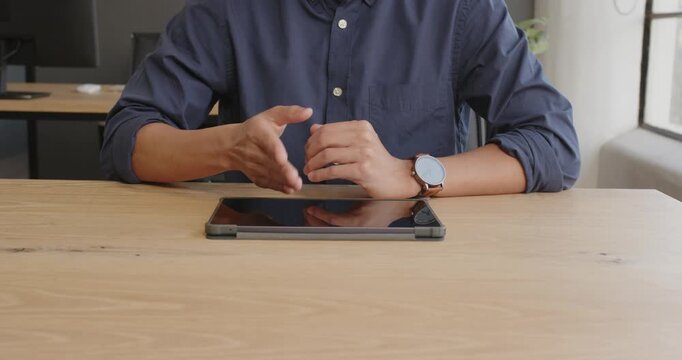 Business professional using tablet at office desk, gesturing during presentation