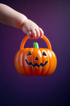 Child's Hand Holds Orange Pumpkin Bucket for Halloween Celebration