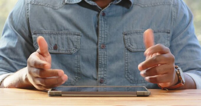 African American man using tablet at desk, wearing denim shirt, focused on work