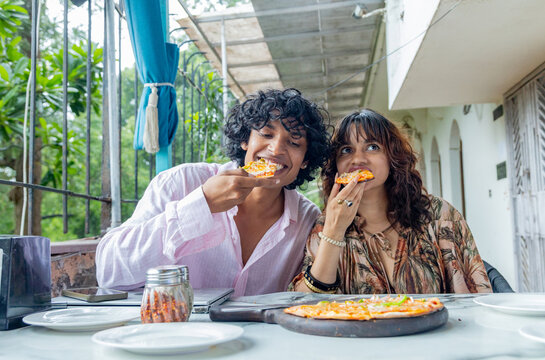 Young Indian Gen Z man and woman enjoying pizza together at a modern caf&eacute;, sharing a casual meal and social moment, friendship, youth lifestyle, urban life in India.