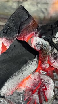 Glowing red charcoal embers burning with hot flames and white ash on a traditional argentinian barbecue grill getting ready for roasting delicious and juicy meat
