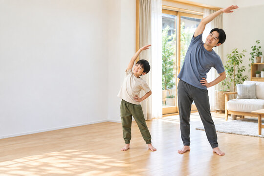 Father and son stretching together in a bright living room，明るいリビングで一緒にストレッチする父親と息子