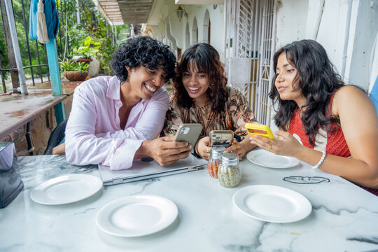 Young indian gen z friends gathering at outdoor cafe checking smartphone for online food order ro sharing a moment of connection while viewing engaging content on a mobile phone, social interaction