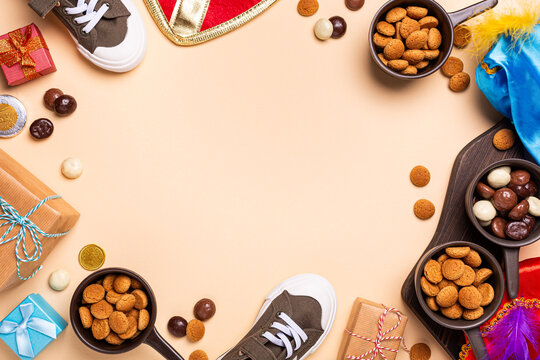 Overhead festive arrangement for Sint Nicholas day, Dutch Sinterklaas shows shoes, wrapped presents, cookies, chocolates, colorful feathers, creating seasonal holiday composition with copy space