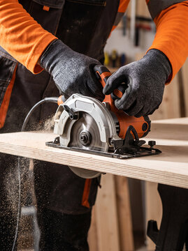 Worker cutting a wooden panel with a circular saw in a workshop. The scene represents skilled carpentry, construction work and precise material preparation