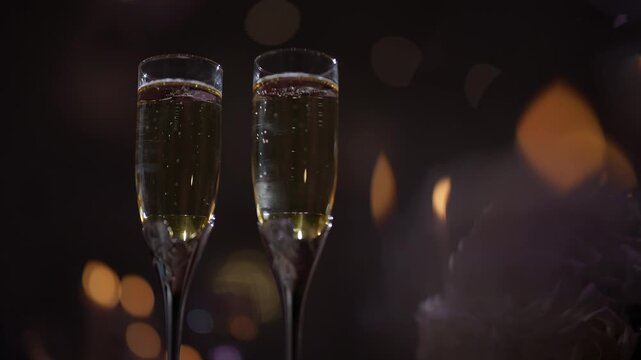 Two elegant champagne flutes filled with sparkling wine against a soft glowing bokeh background