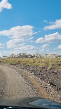 vertical video shot from a car window, transitioning from a side view, showcases the multicolored chalk mountains of Altyn-Emel National Park, Kazakhstan.