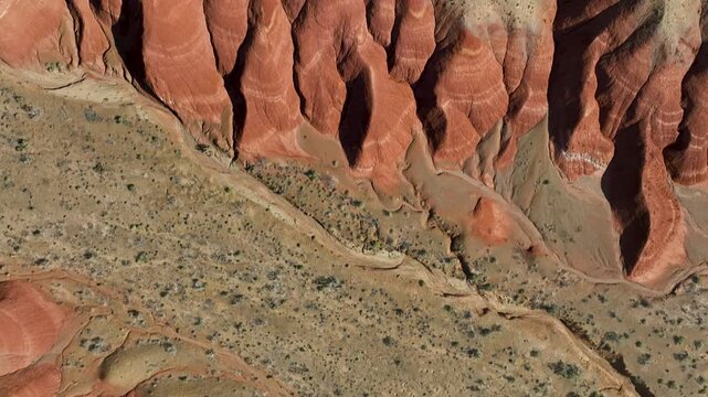 Drone flatlay view above red chalk Aktau Mountains with intricate dried river channels in Altyn Emel National Park, Kazakhstan, showing erosion carved landscape from above.